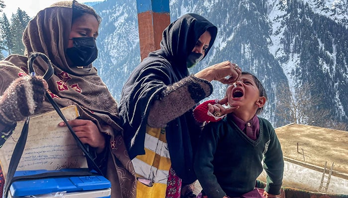 A health worker administers polio drops to a child during a door-to-door vaccination campaign amidst heavy snow in the Bakwali-Surgan area of AJKs Neelum Valley, on February 4, 2025. — AFP