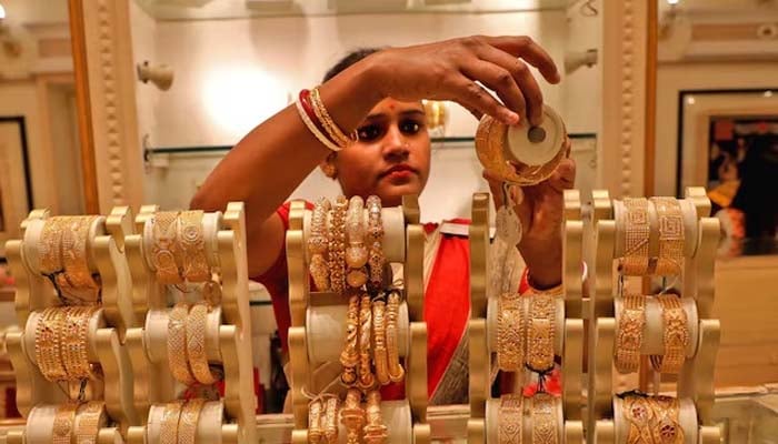 A saleswoman shows gold bracelets to a client in a jewelry exhibition hall on the occasion of Akshaya Tritiya, a large gold buying festival in Kolkata, India, May 3, 2022. - Reuters