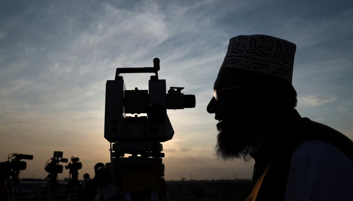 A member of Pakistans moon sighting committee is silhouetted as he uses theodolite to look for the new moon in Peshawar. — Reuters/File