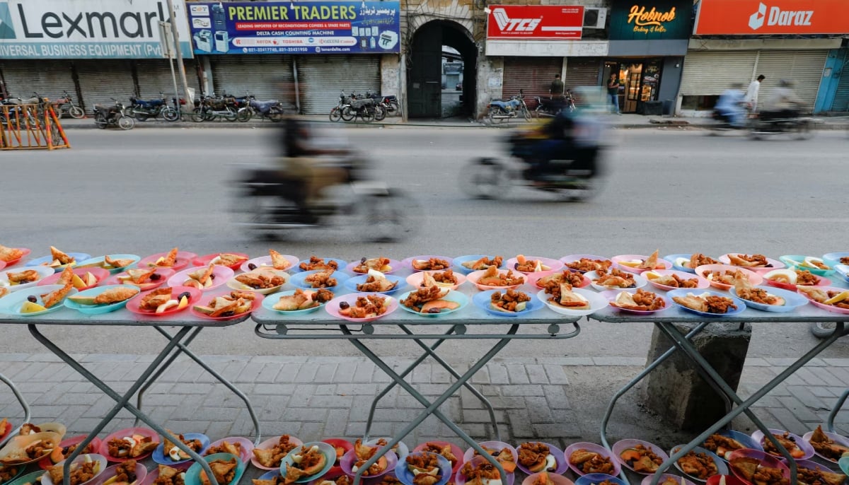 Commuters move past plates of food placed for passersby to break their fast during Ramadan, along a roadside in Karachi. — Reuters/File