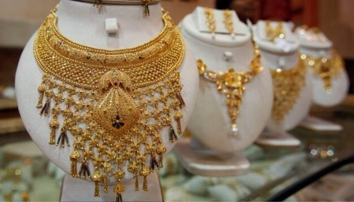 A saleswoman is held behind the gold necklaces presented in an exhibition hall of jewelry in Agartala, capital of the northeast state of Tripipura, August 18, 2010. —Rethers