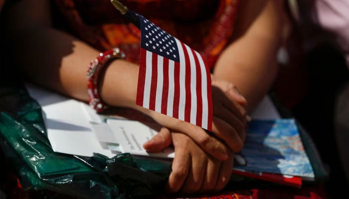 A new American citizen holds a US flag during a naturalisation ceremony . — Reuters/File