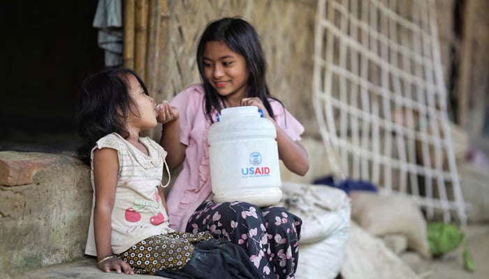 A Rohingya girl feeds a child from a jar with the USAID logo on it, at a refugee camp in Coxs Bazar, Bangladesh, February 11, 2025. — Reuters