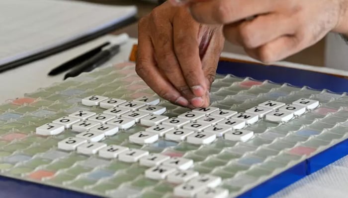 A player places the letter tiles in order to make a word during scrable competition. — AFP