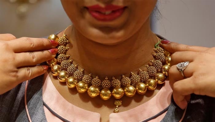 A saleswoman displays a gold necklace to a customer inside a jewellery showroom on the occasion of Akshaya Tritiya, a major gold buying festival, in Mumbai, India April 18, 2018.—Reuters