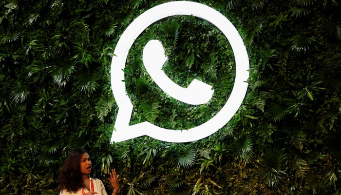 A woman stands next to a logo of messaging application Whatsapp during a Meta conference in Mumbai, India, September 20, 2023. — Reuters