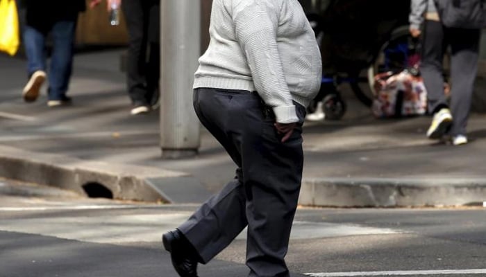 A man crosses a main road as pedestrians walk along the footpath in central Sydney, Australia. — Reuters/File