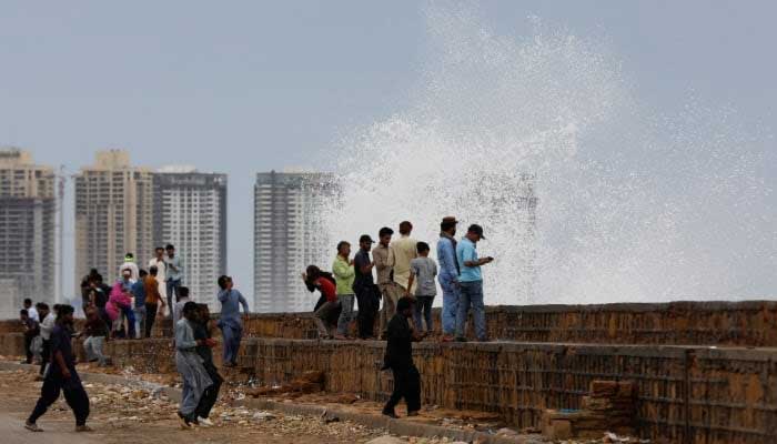 People gather near the rising waves at Sea View in Karachi, June 13, 2023. — Reuters