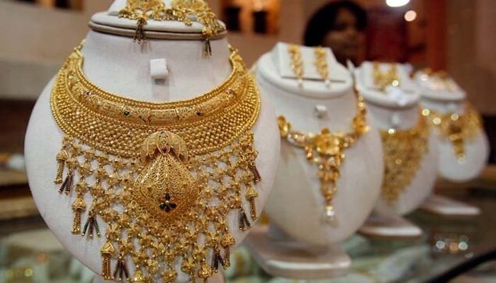 A saleswoman stands behind the showcased gold necklaces at a jewellery showroom in Agartala, capital of Indias northeastern state of Tripura.—Reuters/File