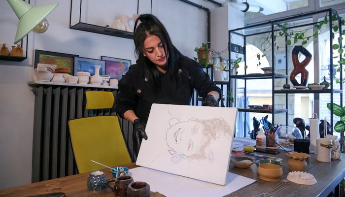 Turkish artist Serap Lokmaci works on a portrait of Hungarian woman Katalin Kollar using ashes from her cremation, in Urgup, central Nevsehir province, Turkey, February 27, 2025. — Reuters