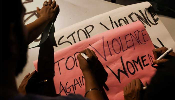 People write slogans on posters before the start of a candlelight vigil condemning the rape and murder of a trainee medic at a government-run hospital in Kolkata, on a street in Mumbai, India, August 14, 2024. — Reuters