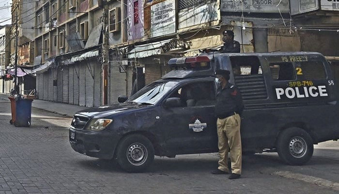 Police personnel stand guard at a commercial market area in Karachi. — AFP/File