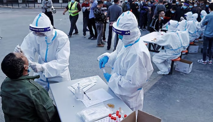 A medical worker in protective suit collects a swab from a resident at a makeshift nucleic acid testing site, following cases of the coronavirus disease (COVID-19) in Shanghai, China March 11, 2022. — Reuters