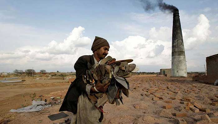 A worker carries shoes to be burned in the kiln of a brick factory in Islamabad, March 9, 2017. — Reuters