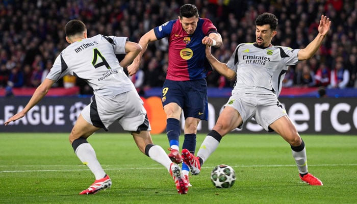 Barcelonas Polish forward #09 Robert Lewandowski (centre) is challenged by Benficas Portuguese defender #04 Antonio Silva (left) and Benficas Portuguese defender #44 Tomas Araujo during the UEFA Champions League Round of 16 second leg football match between FC Barcelona and SL Benfica at the Estadi Olimpic Lluis Companys in Barcelona on March 11, 2025. — AFP