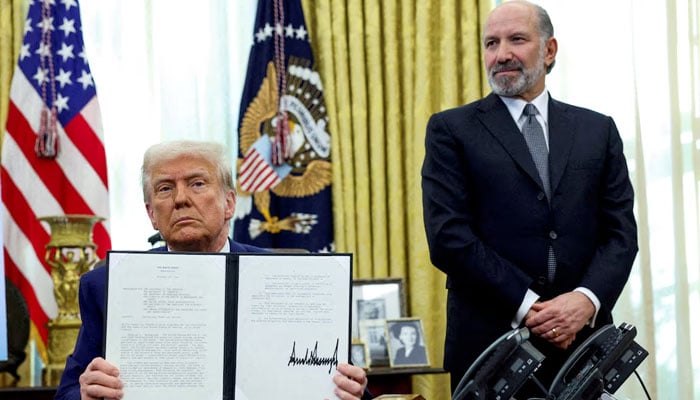 US President Donald Trump holds an executive order about tariffs increase, flanked by US Commerce Secretary Howard Lutnick, in the Oval Office of the White House in Washington, DC,US on February 13, 2025. — Reuters