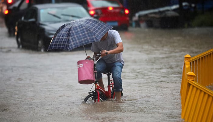 A man rides a bike through a flooded street in Hangzhou, Zhejiang province, China, August 26, 2017. Picture taken August 26, 2017. — Reuters