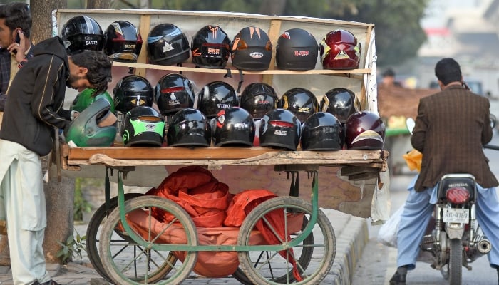 A vendor is busy in repairing out of order helmet at his roadside workplace. — Online/ File