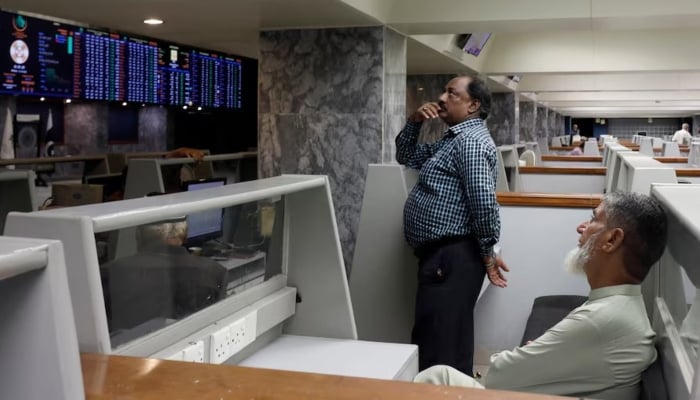 Stock brokers monitor new on television screen at a booth, during a trading session at the Pakistan Stock Exchange, in Karachi, July 3, 2023. — Reuters