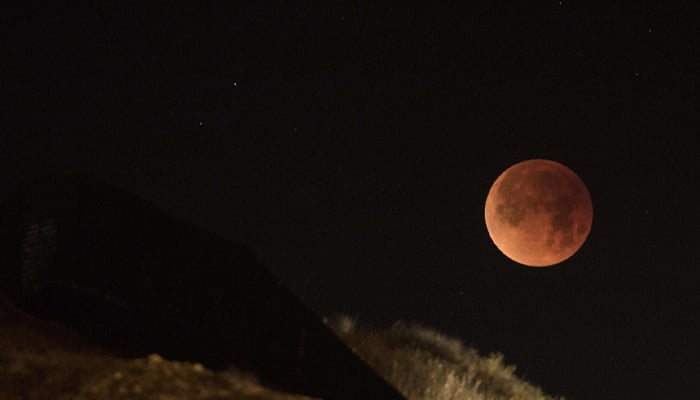 A blood moon seen over a hill. — AFP/File