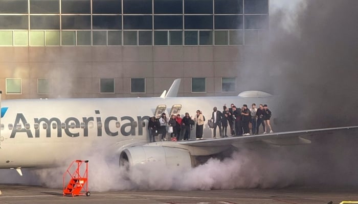 Passengers standing on the wing of an American Airlines plane as they are evacuated after it caught fire while at a gate at Denver International Airport in Denver, Colorado, March 13, 2025. — AFP