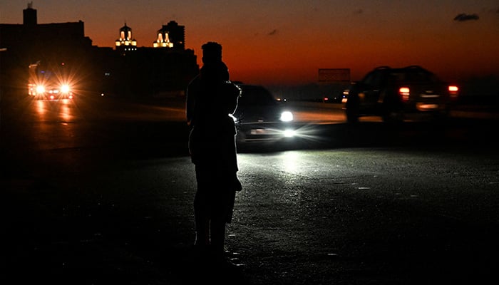 A couple of Cubans walk on a street during a nationwide blackout caused by a grid failure in Havana on March 15, 2025. — AFP