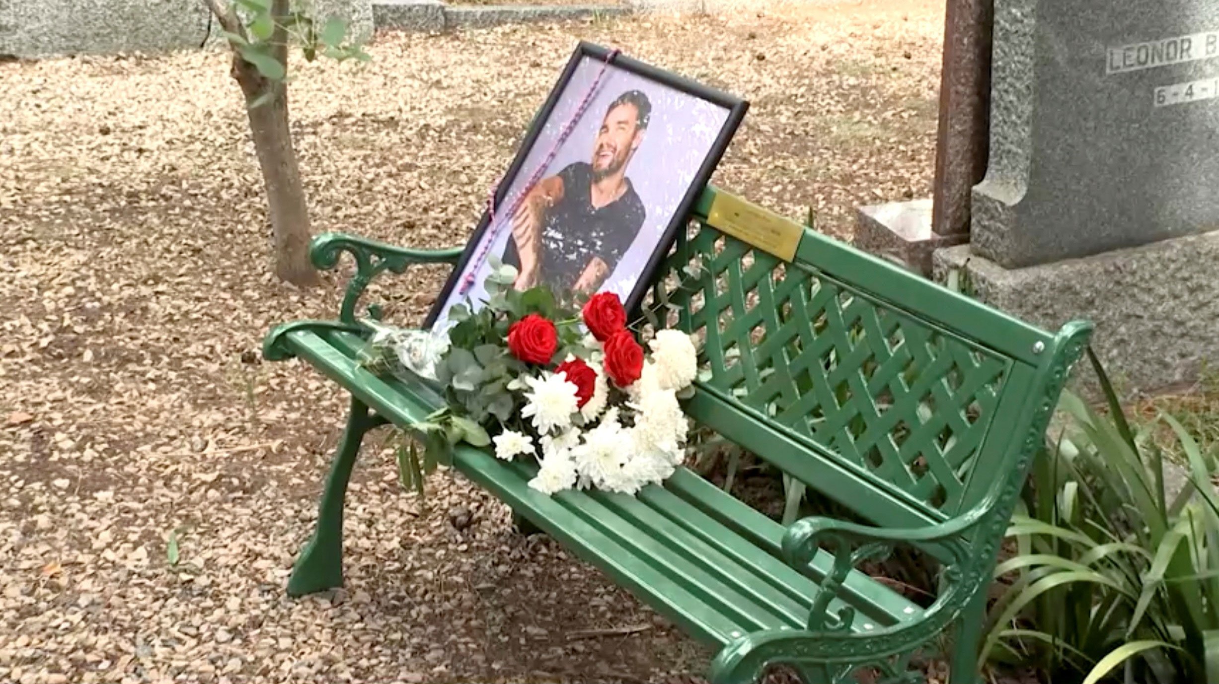 A portrait of late British singer Liam Payne and flowers sit on a bench unveiled by One Direction fans at the British Cemetery in Buenos Aires, Argentina March 16, 2025, in this screen grab from video. REUTERS/Reuters TV