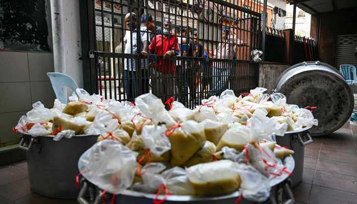 People Queue Outside The Gate of the Indian Mosque for the Popular Dish Bubur Slow During Ramadan in Kuala Lumpur, Malaysia on March 7, 2025. - AFP