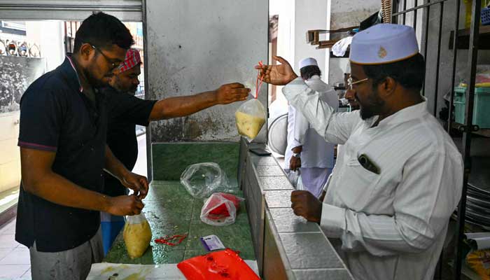 An Indian Muslim Man Receives a Packet of the Popular Dish Porridge Swambuk At Mosque India During Ramadan in Kuala Lumpur, Malaysia on March 7, 2025. - AFP