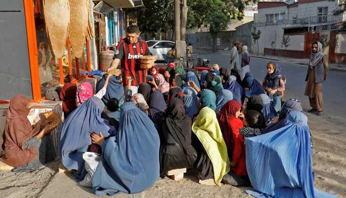 An Afghan girl receives a loaf of bread in front of a bakery among the crowd in Kabul, Afghanistan, August 5, 2022. — Reuters