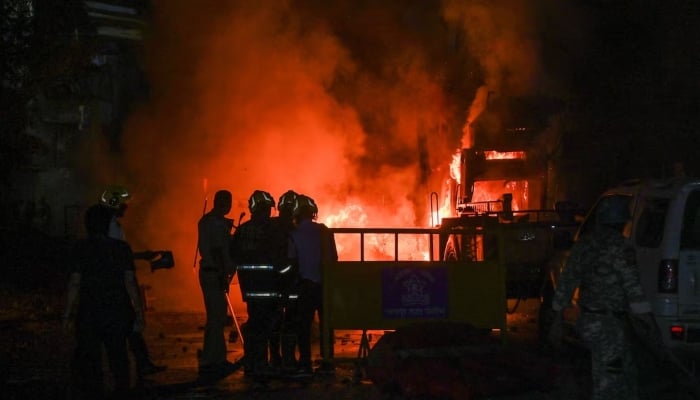 Members of police stand as vehicles burn after clashes erupted due to demands over removal of the tomb of Mughal emperor Aurangzeb, in Nagpur, India, March 17, 2025. — Reuters