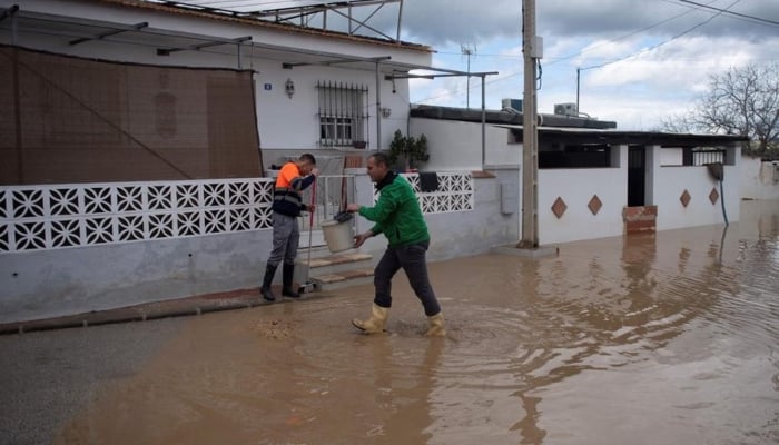 Residents cleaning a street flooded in Cartama, near Malaga, southern Spain, on March 18. — AFP