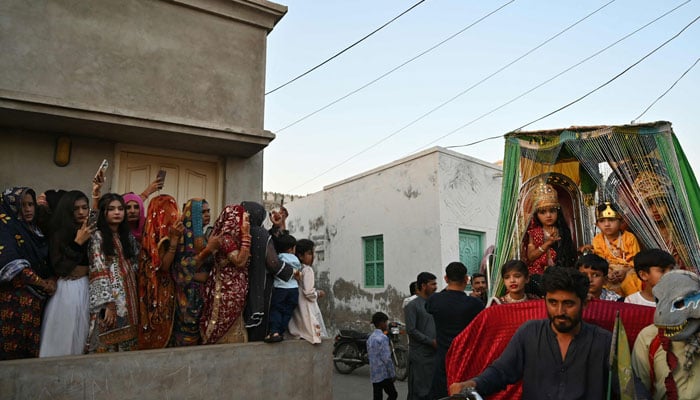 Hindu women watch the procession as they celebrate Holi in Tharparkar district on March 13, 2025. — AFP