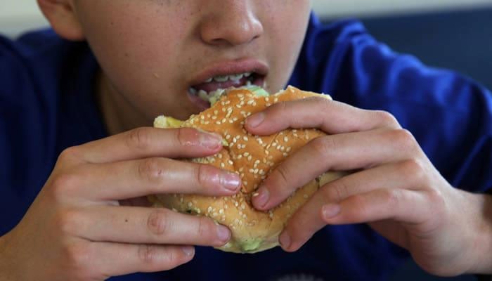 A boy eating a burger.— fao.org/File