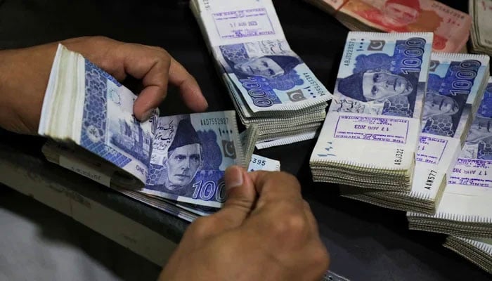 An employee has Pakistani Roupie tickets in a Peshawar bank on August 22, 2023. - Reuters