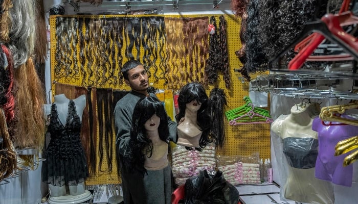 An Afghan shopkeeper displaying womens wigs at his shop in Kabul on March 13, 2025. — AFP