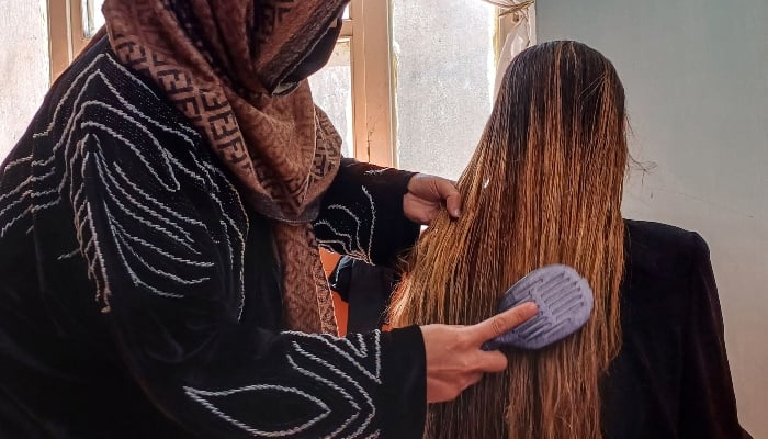 An Afghan woman hairdresser (left) combing her clients hair at a salon in Kabul on March 3, 2025. — AFP