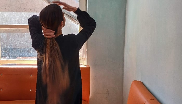 An Afghan woman adjusting her hair at a salon in Kabul on March 3, 2025. — AFP