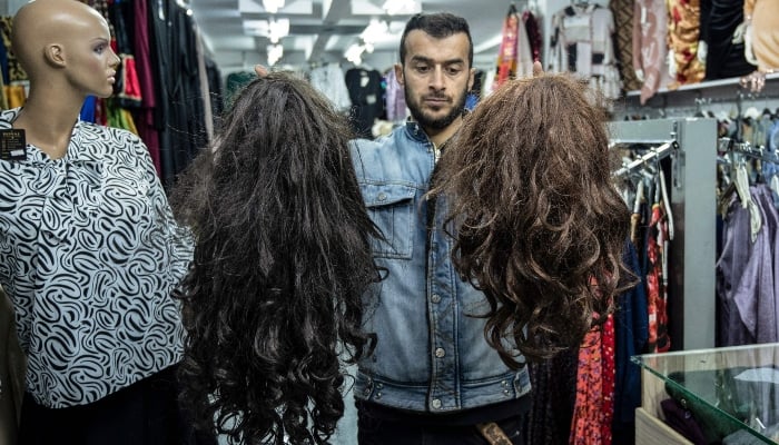 An Afghan shopkeeper displaying womens wigs at his shop in Kabul on March 13, 2025. — AFP