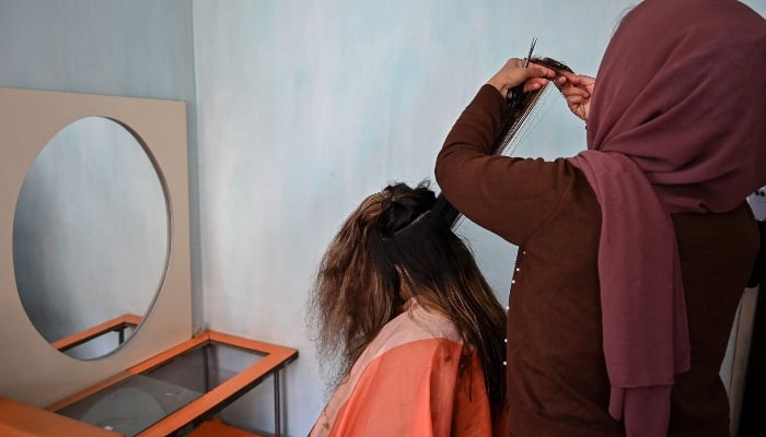 An Afghan woman hairdresser (right) giving a haircut to her client at a salon in Kabul on March 19, 2025. — AFP