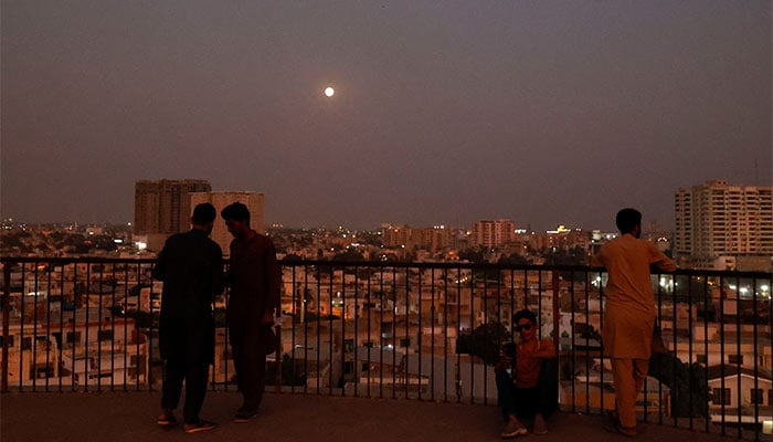 Representational image shows men standing at a terrace while moon shines on the sky in Karachi on November 15, 2024. — Reuters