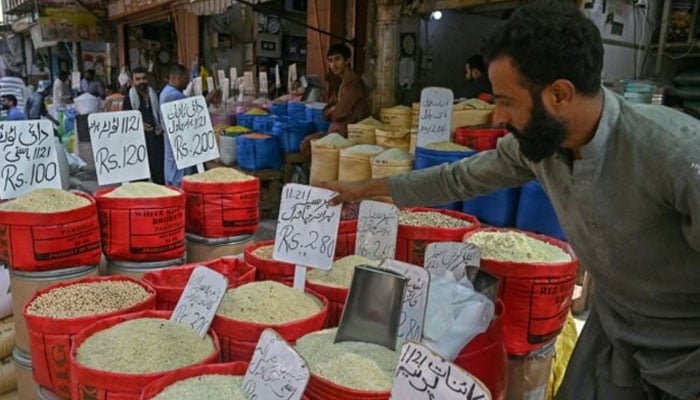 A shopkeeper arranges price tags his grocery shop in Karachi on September 26, 2024. — AFP